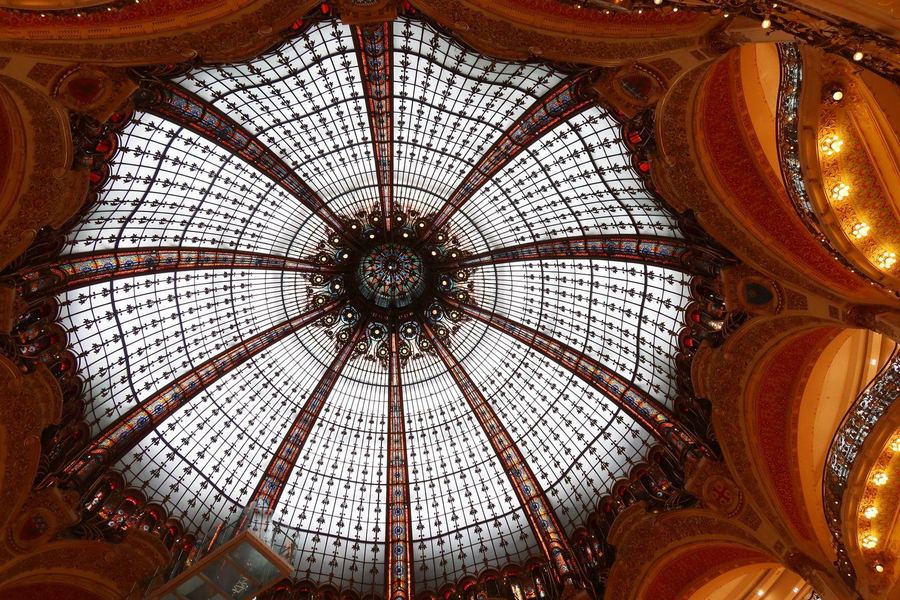 Looking straight up into the stained-glass dome of the Galeries Lafayette, with gilded balconies curving around it