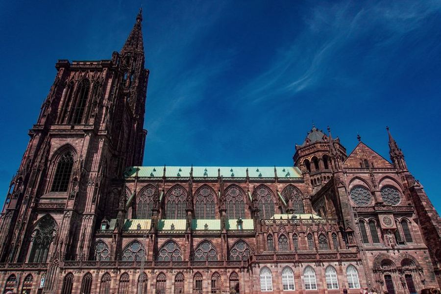 The pink sandstone flank and single spire of Strasbourg's gothic cathedral against a clear blue sky