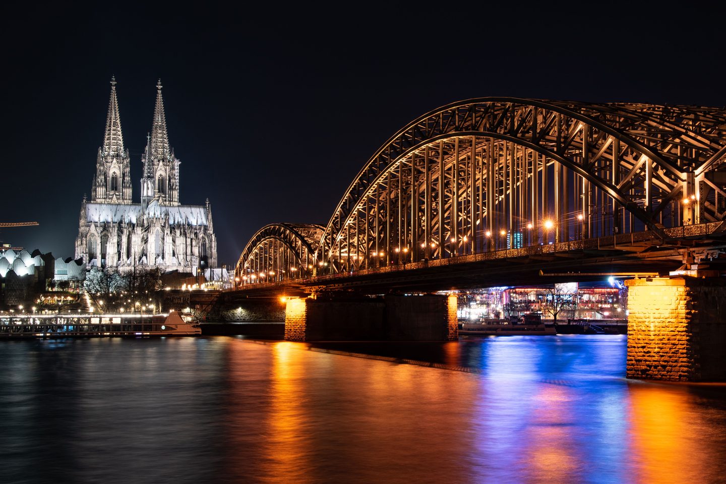 Cologne Cathedral and the Hohenzollern bridge lit at night over the Rhine