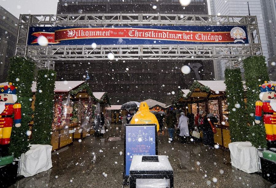 Snow falling on the entrance arch of Chicago's Christkindlmarket, with wooden huts and two giant nutcracker figures either side